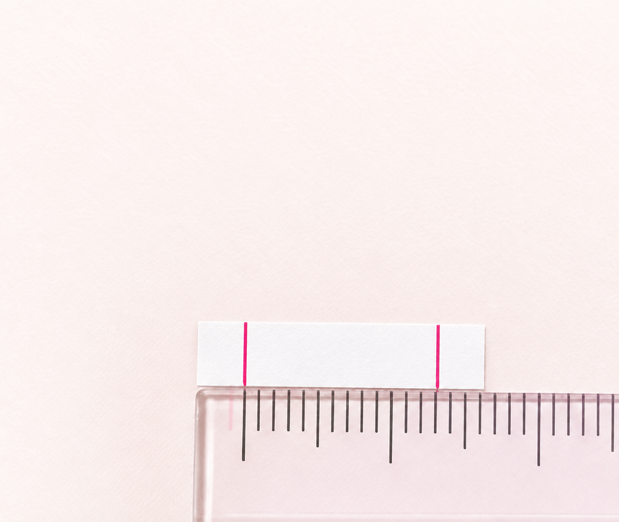 A marked paper strip measured against a translucent pink ruler